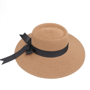 Close-up of fine straw weave texture and elegant black grosgrain ribbon bow on wide brim hat