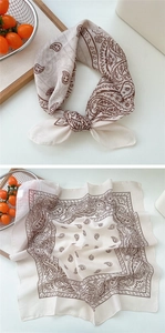 Detail of soft cotton-linen square scarf with classic brown paisley pattern and knotted styling