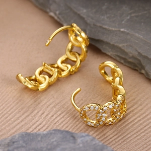 Macro detail of 18k gold plated chain earrings with sparkling zircon stones on linen