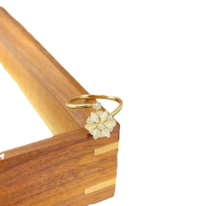 Rotating cat-eye flower ring in gold with white petals and sparkling crystal center