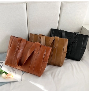 Three PU leather tote bags in brown, khaki, and black colors displayed on a bed