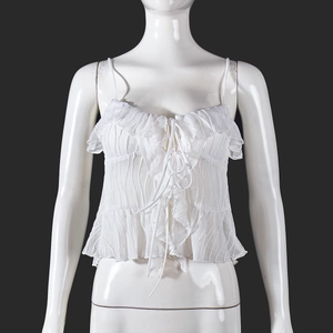 Detail view of white pleated crop top featuring front ribbon bow and strap texture