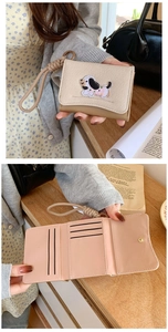 Close-up of beige dachshund embroidery wallet with pink interior and wrist strap
