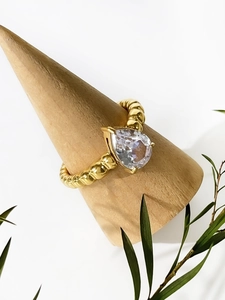 Close-up of pear-cut zircon on 18K gold-plated beaded band ring on wood stand