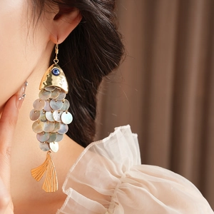 Detailed shot of vintage fish earrings with shell scales and gold tassel hanging details