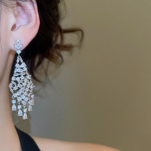 Détail de boucles d'oreilles à pompons argentés avec zircons étincelants en poire