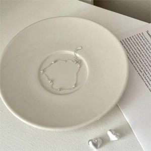 Minimalist S925 silver pearl bracelet displayed on a ceramic dish with aesthetic props