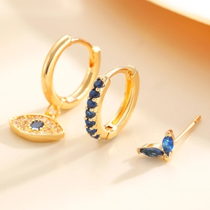 Macro shot of gold Evil Eye hoop earrings and stud set with blue and white crystals