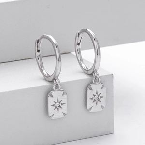 Macro shot of silver S925 earrings with sparkling zircon eight-pointed star pendant