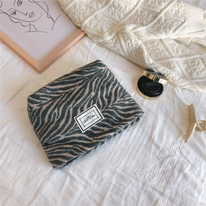 Close-up of zebra pattern canvas clutch bag with Time To Party label on a soft bed