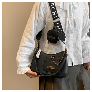 Detail of black lychee grain crescent bag with broad branded strap and gold chain
