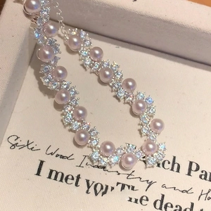 Macro shot of elegant pink pearl bracelet with wavy zircon-encrusted silver links