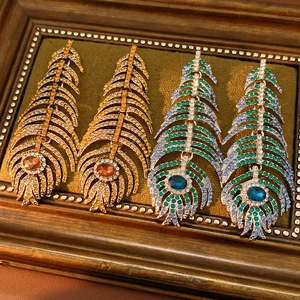 Macro detail of vintage feather earrings with sparkling diamonds on green velvet