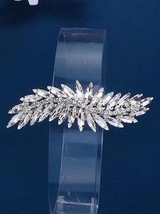 Detailed view of silver feather hair clip with sparkling rhinestones on dark blue background