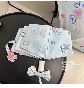 Close-up of light blue automatic umbrella with butterfly prints and bow pendant charm