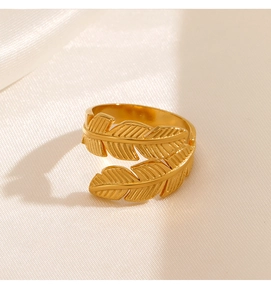 Macro shot of gold double feather open ring on white silk fabric with sharp details