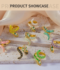 Various colorful enamel snake rings with rhinestones on a decorative stone platform