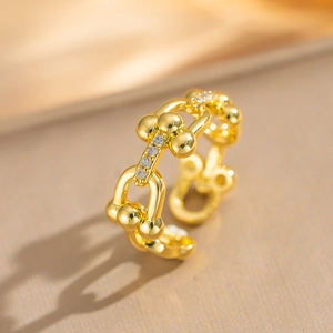 U-shaped horseshoe gold-plated ring with shimmering zircons on champagne silk