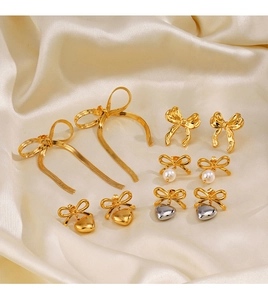 Détail de boucles d'oreilles nœuds dorés avec perles et cœurs sur tissu en soie élégant