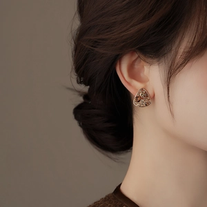 Close-up of vintage hollow triangle stud earrings with glittering brown crystals