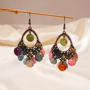 Detail of vintage bohemian teardrop earrings with colorful shell inserts and bronze metalwork