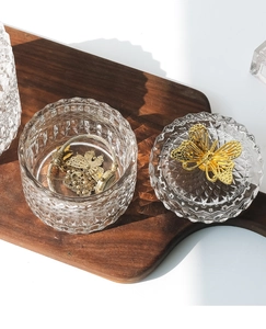Detail of relief glass storage jar with a gold butterfly handle and diamond cut texture