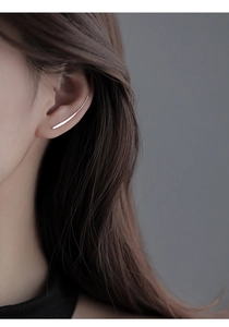 Close-up of a minimalist silver ear crawler showing a sleek curved design on a model