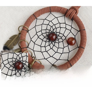 Macro shot of handcrafted leather dreamcatcher car charm with brown feathers and beads