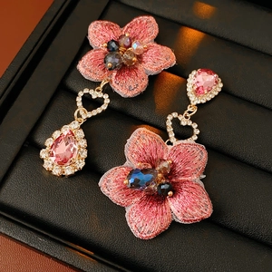 Détail de boucles d'oreilles fleurs en tissu rose avec gemmes gouttes et attaches en cœur