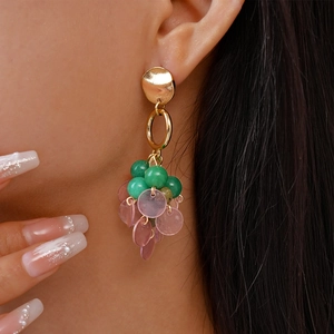 Detail of vintage gold drop earrings with green beads and pink translucent discs on model