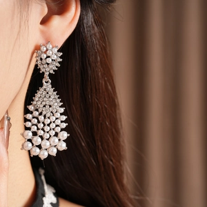 Close-up of chandelier teardrop earrings with white pearls and crystals on silver needles