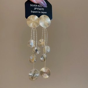 Detail of 925 silver golden long tassel earrings with radiant sunburst texture