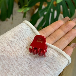 Detail of a small red acetate hair claw clip featuring golden FRANCE Handmade lettering