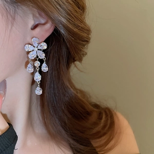 Close-up of silver flower earrings with zircon waterdrop tassels worn by a model