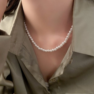 Gros plan d'un collier de perles vintage sur un mannequin en chemise de soie