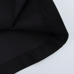 Close-up detail of the black twill fabric texture and stitched hem on the sleeveless vest