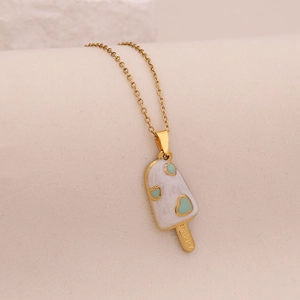 Macro shot of gold ice cream pendant with white enamel, heart motif and Happy engraving
