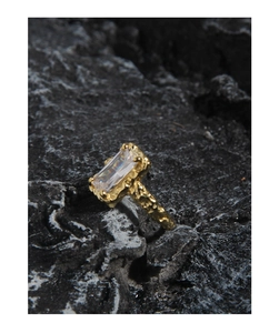 Macro detail of gold S925 silver ring featuring irregular rock texture and a rectangular gem