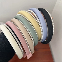 Close-up of assorted pearl-edged headbands in various colors held by a hand