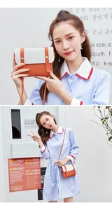 Detail view of stylish color-block crossbody bag in white and orange with gold metal rivets