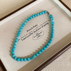 Close-up of turquoise beaded necklace with irregular stone pendant on a jewelry tray