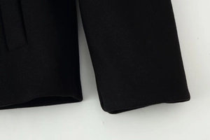 Detailed close-up showing high-quality wool fabric texture and stitching on black coat sleeve
