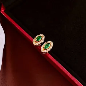 Retro oval earrings with green marquise gemstone and white zircon in a golden setting