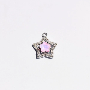 Detailed macro of silver star pendant with pink floral inlay and sparkling crystals