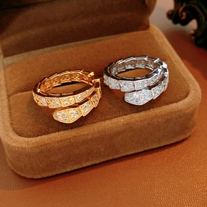 Detailed view of luxury snake-shaped rings with white zircon inlays on brown velvet