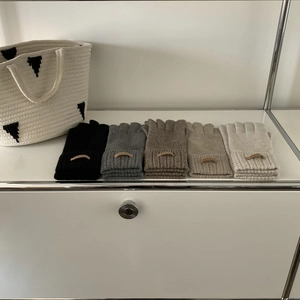 Flat lay of knit wool gloves in five colors with Hand Made labels on a white shelf
