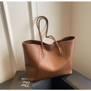 Close-up of minimalist brown PU leather tote bag with elegant shoulder straps