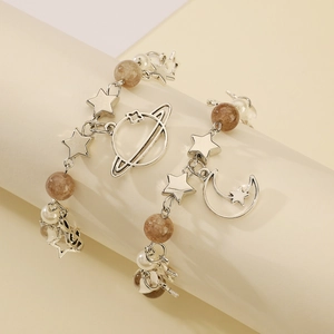Detail of star, moon, and planet charms with earth-toned beads on silver earrings