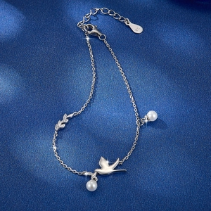 Macro view of S925 silver bird bracelet with sparkling zircon leaves and a pearl charm