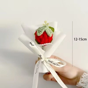 Close-up of a handmade crochet strawberry bouquet in white paper wrap, 15cm height